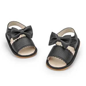Detailed view of black PU baby sandals with bow decoration and scalloped edges