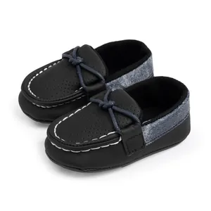 Detail von Baby-Mokassin mit perforierter Spitze, grauem Denim-Stoff und weißen Nähten