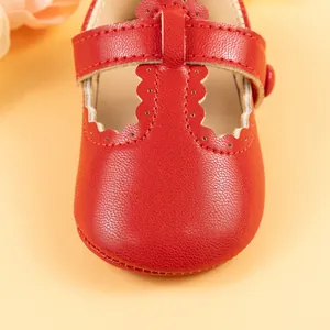 Detailed close-up of red Mary Jane baby shoes with scalloped edges and cutout patterns