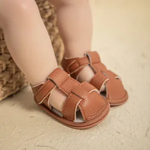 Close-up of brown litchi leather baby sandals with woven straps and velcro closure