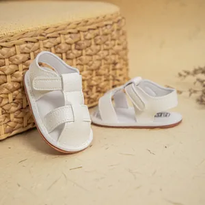 Close-up of white baby sandals with velcro straps and brown soft non-slip rubber soles