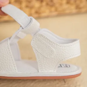 Detailed close-up of white baby sandals showing the soft leather texture and velcro strap