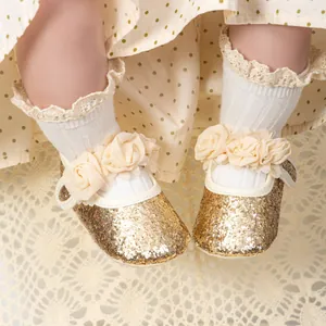 Detail of baby girl Mary Jane shoes with gold sequins and 3D fabric flower decorations