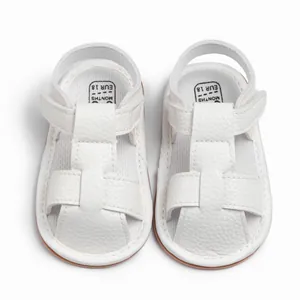 Close-up of white baby sandals with litchi texture leather and velcro strap detail