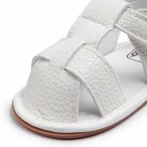 Macro detail of white PU leather baby sandals featuring woven cross straps and closed toe