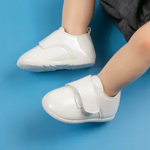 Dettaglio scarpe neonato in vernice bianca con chiusura a strappo e suola antiscivolo