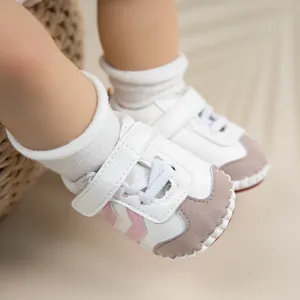 Detail view of baby walker shoes with pink stripes and velcro strap on a woven rug