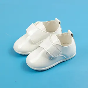 Dettaglio scarpe neonato in pelle verniciata bianca con pratica chiusura a strappo regolabile