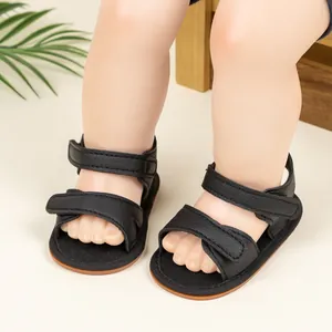 Detailed view of black textured leather baby sandals with double velcro straps for infants