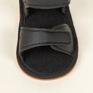 Detailed macro view of black leather baby sandals featuring double velcro straps