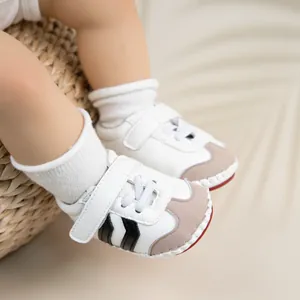 Close-up of baby sneaker with white PU leather and signature triple stripe design