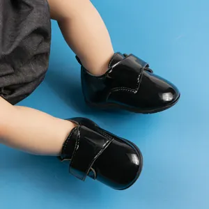 Dettaglio scarpe neonato in pelle verniciata nera con velcro e suola morbida