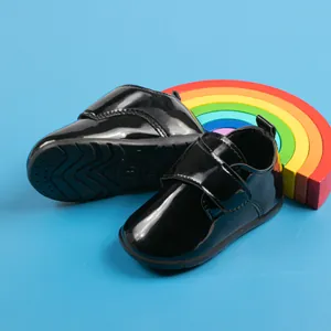 Dettaglio di scarpe per neonati in pelle verniciata nera lucida con velcro e suola in gomma