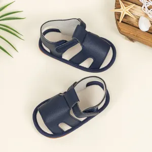 Top view of navy blue baby sandals with hook-and-loop straps and summer beach decor