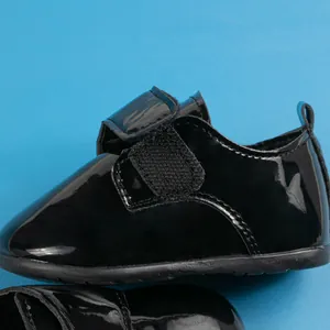 Dettaglio scarpe neonato in pelle verniciata nera con pratica chiusura a strappo