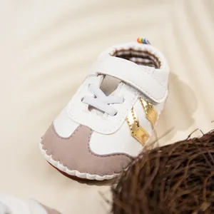 Detail of baby sneakers featuring white PU leather, velcro strap, and gold side accents