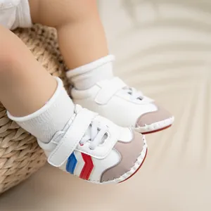 Close-up of white baby walker shoes with red blue side stripes and soft PU soles