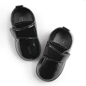 Dettaglio di scarpe per neonati in vernice nera con chiusura a strappo in velcro
