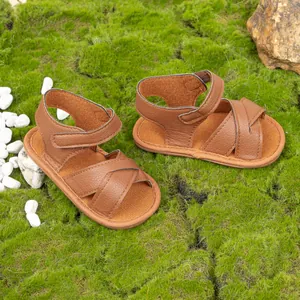 Detailed view of brown leather baby sandals with cross straps and velcro ankle closure