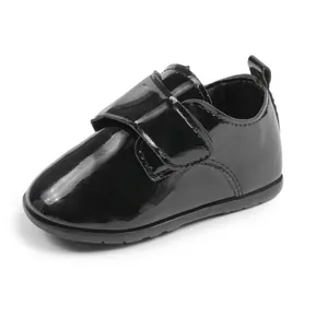 Dettaglio scarpe neonato in pelle verniciata nera con pratica chiusura a strappo