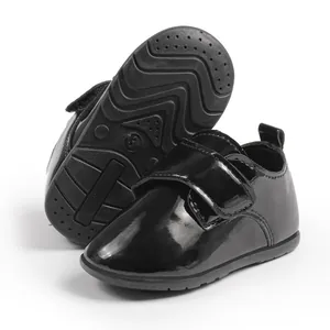 Dettaglio scarpe neonato in pelle verniciata nera con velcro e suola antiscivolo