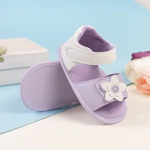 Dettaglio di sandali per neonata con fiore 3D e chiusura in velcro su scatola regalo bianca