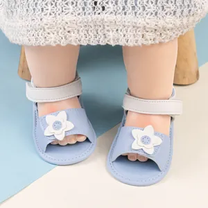 Dettaglio di sandali azzurri per neonata con fiore bianco e cinturino a strappo