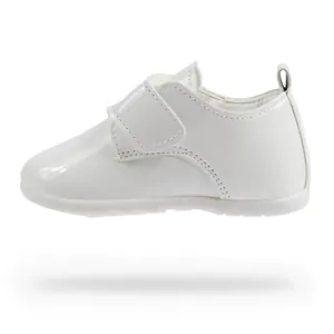 Dettaglio di scarpe per neonati in pelle verniciata bianca con velcro e linguetta