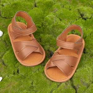 Detail view of brown leather baby sandals with textured cross straps and velcro strap