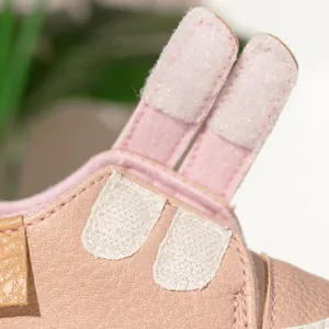 Detail view of pink leather baby shoes with lychee texture and double velcro straps