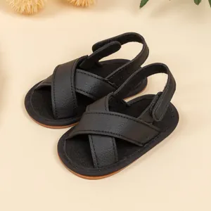 Macro detail of black faux leather baby sandals with adjustable velcro strap and soft sole