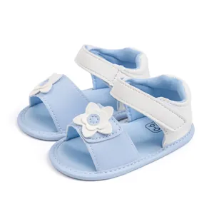 Dettaglio di sandali per neonata con decoro floreale bianco e cinturino blu