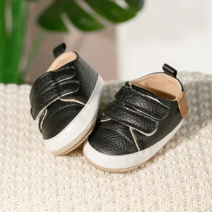 Detail of infant walking shoes with black pebbled leather and white velcro straps