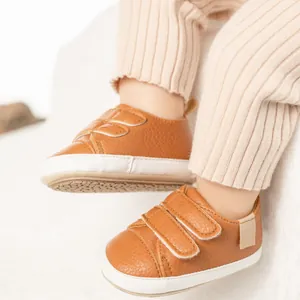 Close-up of brown textured leather baby shoes with white rubber anti-slip soles
