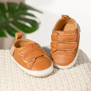 Detail of caramel leather baby shoes with double hook-and-loop straps and soft rubber soles