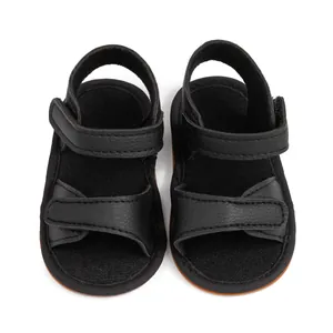 Detail of black infant sandals with dual hook-and-loop straps and textured faux leather