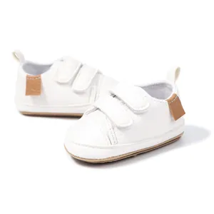 Detail of white faux leather baby shoes with double hook-and-loop straps and non-slip sole