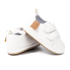 Unisex white faux leather baby walking shoes with brown rubber soles and velcro straps