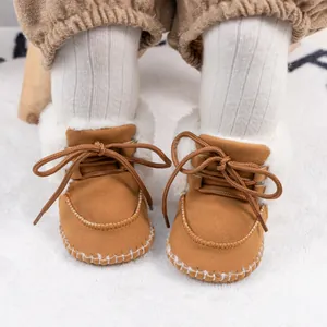 Detail of baby winter boots with camel suede, white faux fur trim and hand-stitched seams