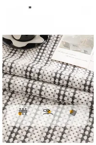 Close-up of gray chenille sofa cover with woven texture, coffee cup and postcard