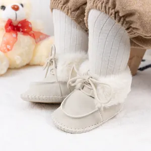 Detailed view of beige suede baby winter boots with plush faux fur trim and laces