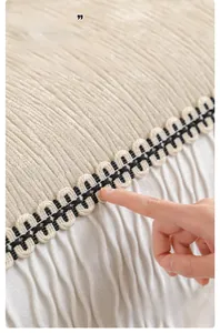 Detail of chenille sofa cover showing beige stripe velvet with ruffled white lace trim