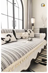 Detail of chenille sofa cover with black and white grid pattern and elegant cream fringe