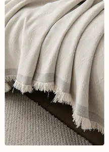 Detail of cream chenille sofa cover showing diamond weave texture and white fringe tassels