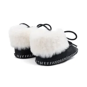 Detail of baby winter boots featuring black suede texture, faux fur trim, and stitched sole