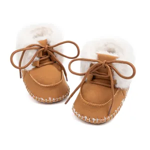 Detail showing the brown suede baby boots with warm white faux fur lining and round laces