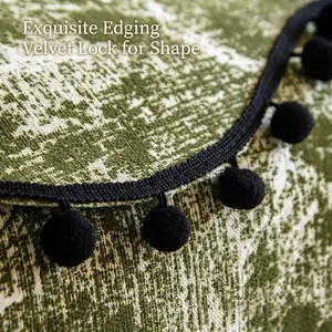 Textured chenille sofa cushion with green jacquard pattern and black pom-pom fringe edges