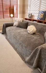 Détail du jeté de canapé en chenille gris foncé avec rayures verticales et franges