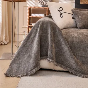 Jeté de canapé en velours côtelé gris foncé avec franges décoratives sur un canapé
