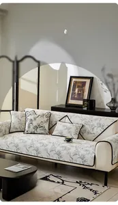Détail d'un coussin de canapé en chenille avec motif floral et liseré noir style crème